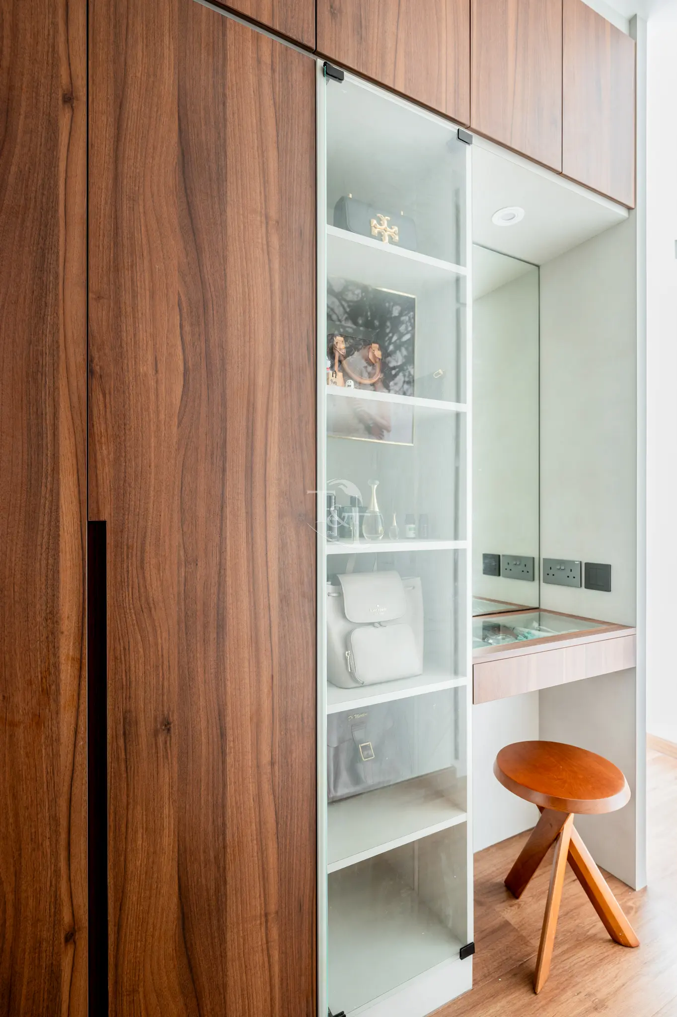 Wood-paneled wardrobe with glass display and vanity desk.